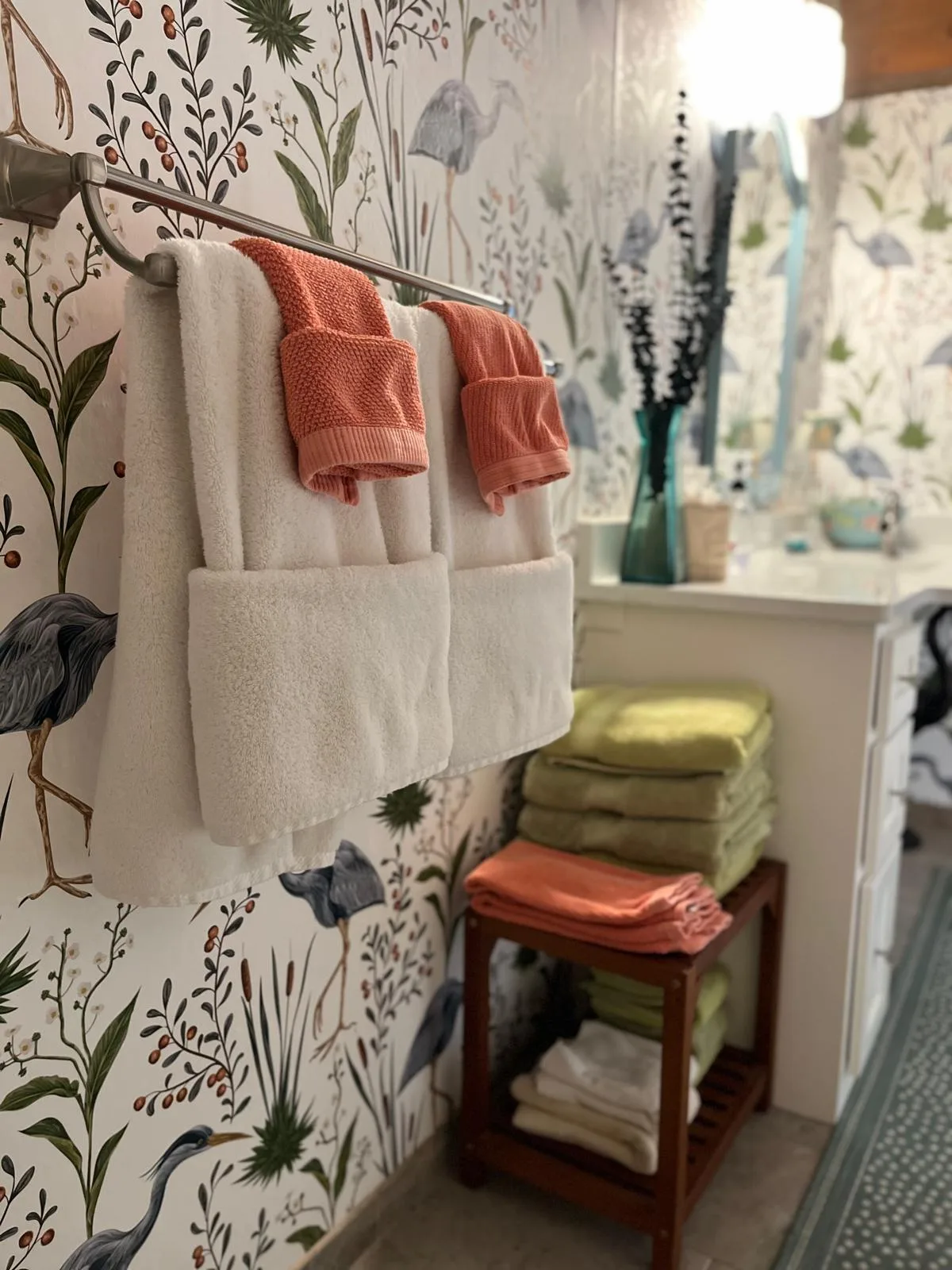 Fresh towels neatly hung and folded in a bathroom with heron wallpaper