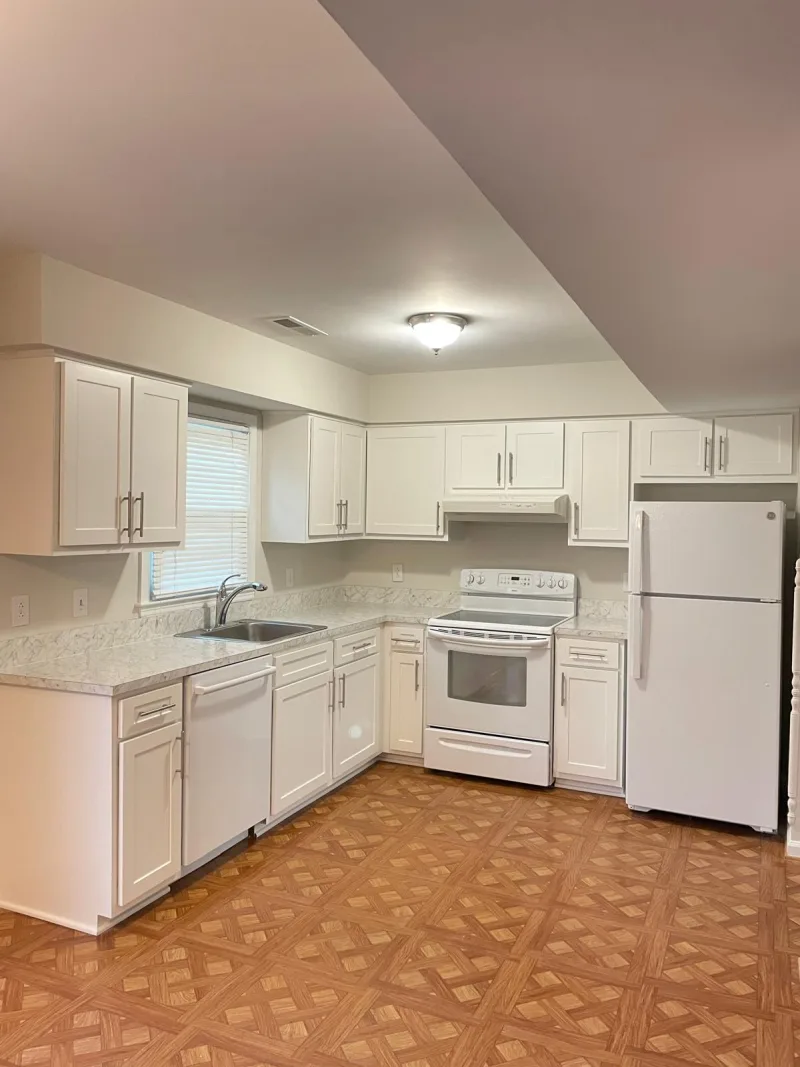 Clean kitchen with white cabinets and white appliances